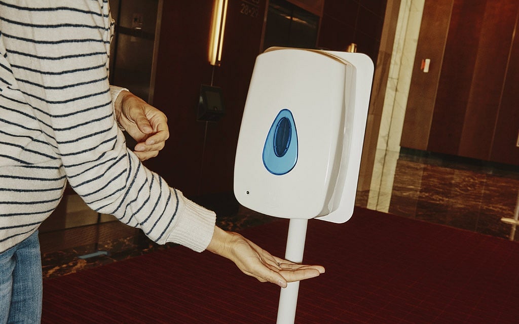 A hand sanitizer dispenser next to a bank of elevators at the Prudential Center in Boston, June 22, 2020. The elevator ride, a previously unremarkable 90 or so seconds, has become a daunting puzzler in the calculus of how to bring people back to work safely after the coronavirus pandemic kept them home for months. (Tony Luong/The New York Times) 