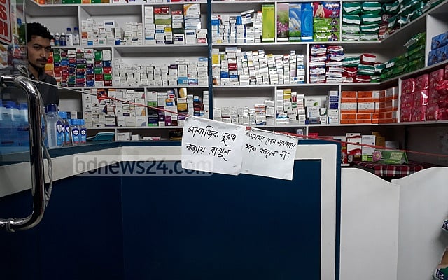 A medicine shop posts a notice to maintain social distancing, but nobody wears a mask in the shop. 