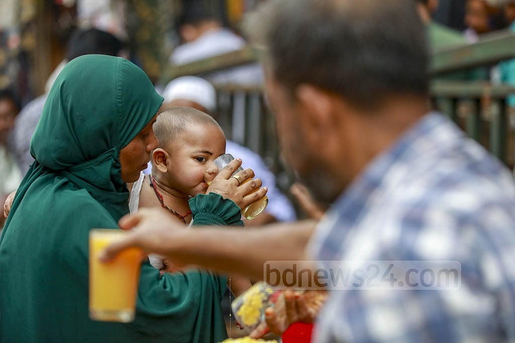 A mother gives her child Bengal quince juice in Dhaka’s Gulistan amid hot weather. Photo: Mahmud Zaman Ovi 