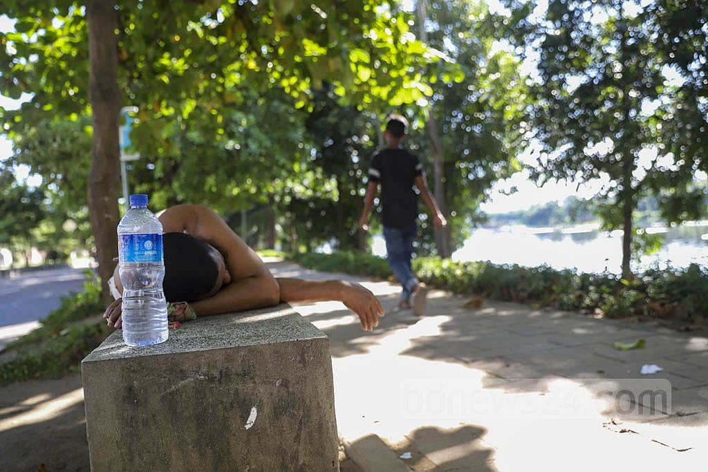 A man takes a nap on a bench under a tree at Hatirjheel in Dhaka on a scorching afternoon on Thursday, Sep 30, 2021. Photo: Mahmud Zaman Ovi 
